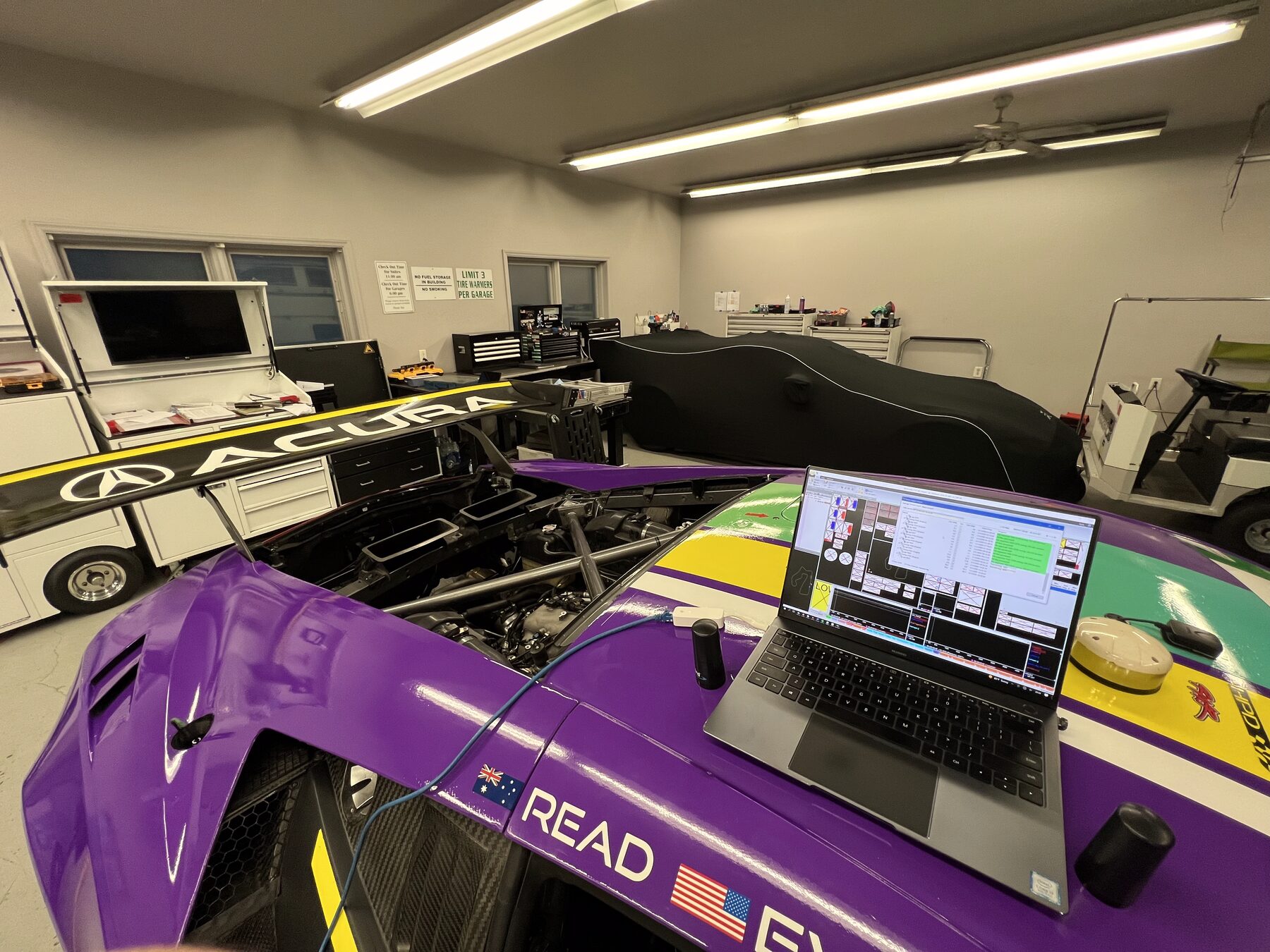 Race car in the garage with bodywork removed and an engineering laptop connected
