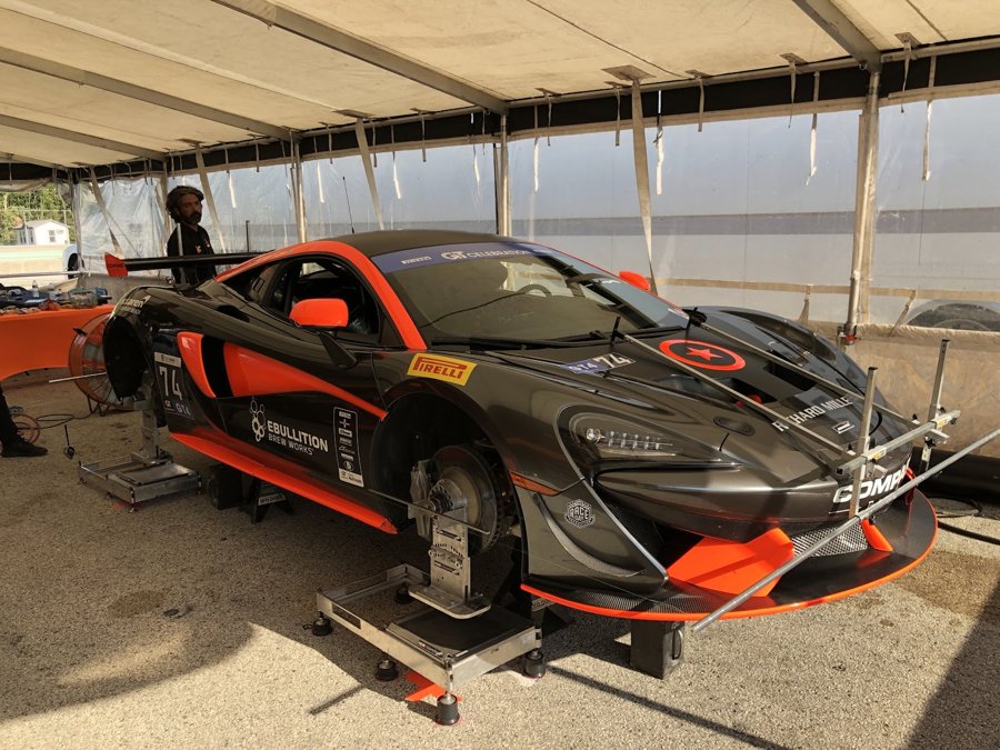 McLaren 570S GT4 on setup pads under the paddock tent