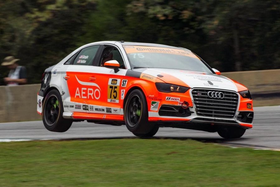 Orange and white Audi number 75 riding the curbs at corner exit