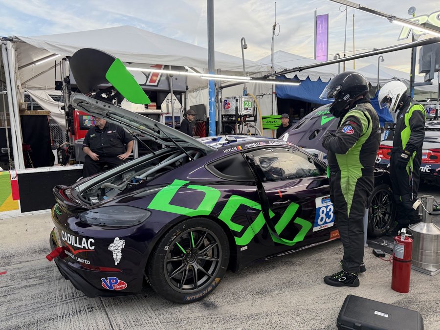 Purple and green Porsche Cayman GT4 number 83 in the paddock with drivers suited up