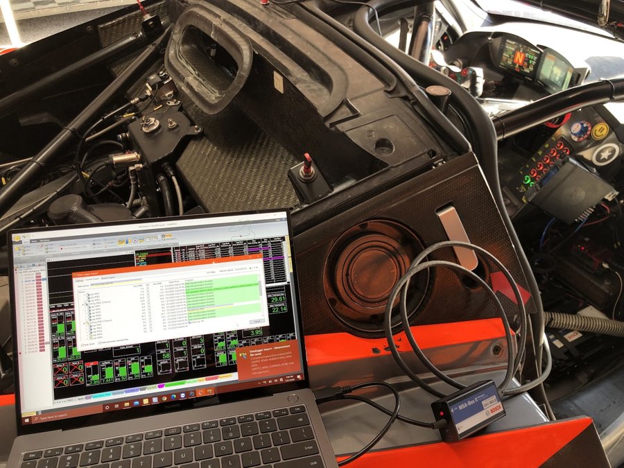 Laptop showing live timing propped in the open cockpit of a race car