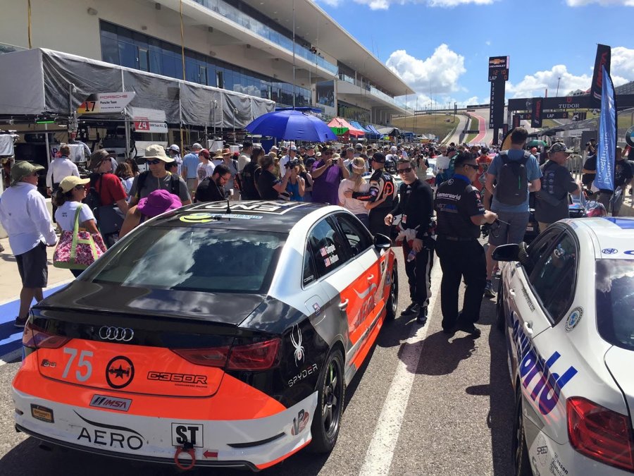 Crowded grid walk with race cars surrounded by spectators before the start