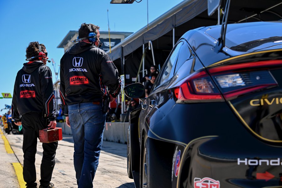 Honda crew walking beside a black Civic race car in pit lane