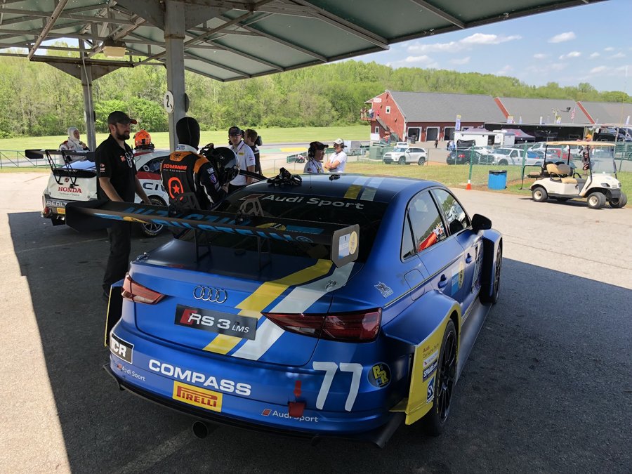Blue and yellow Audi RS3 LMS number 77 being rolled through the paddock