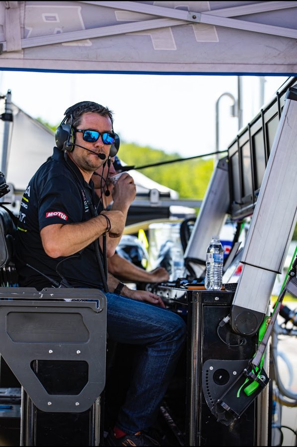 Engineer with a headset making a radio call from the pit stand